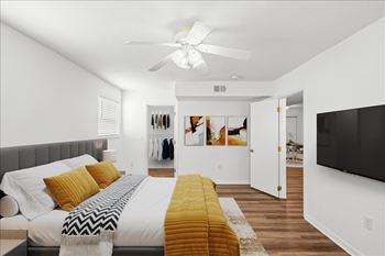 A bedroom with a bed, a ceiling fan, and a clothing rack.